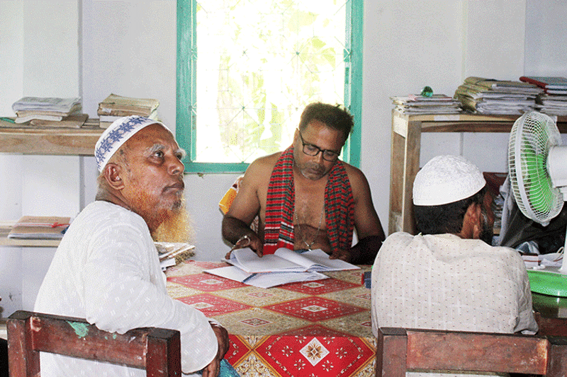 তহসিলদার মনিরুজ্জামান শার্ট খুলে, গলায় গামছা জড়িয়ে লুঙ্গী পরা অবস্থায় অফিসে ডিউটি করেন